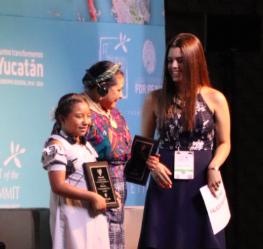 Andrea Peña receiving her award from Nobel Peace Prize laureate, Rigoberta Menchú Tum, alongside fellow 2019 recipient Xóchitl Cruz López.